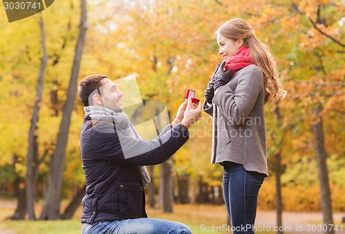 Image of smiling couple with engagement ring in gift box