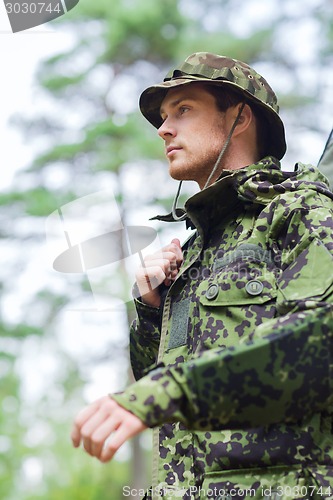 Image of young soldier or hunter with gun in forest