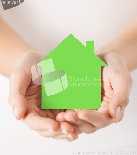 Image of hands holding green paper house