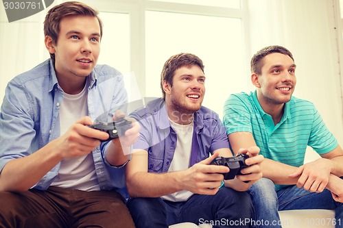 Image of smiling friends playing video games at home