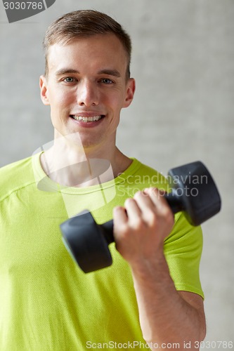 Image of smiling man with dumbbell in gym