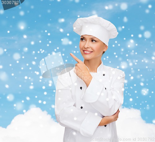 Image of smiling female chef dreaming pointing finger up