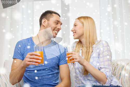 Image of smiling happy couple at home drinking juice