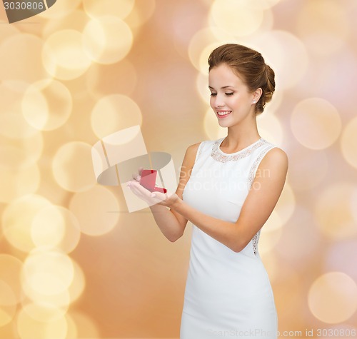 Image of smiling woman holding red gift box with ring