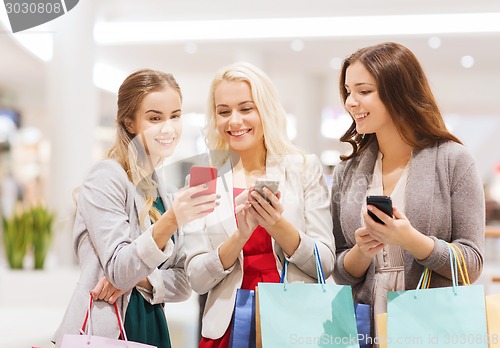 Image of happy women with smartphones and shopping bags