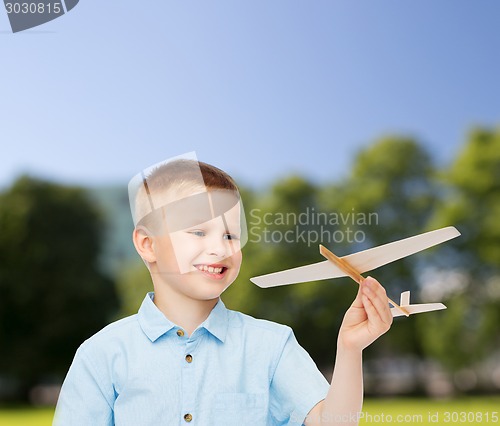 Image of smiling little boy holding a wooden airplane model