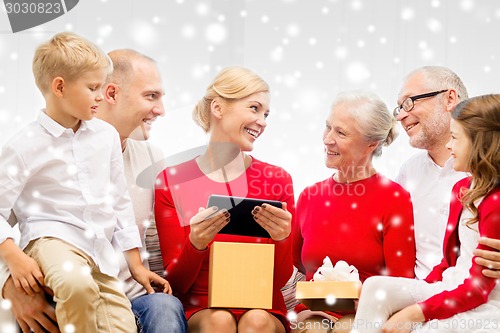 Image of smiling family with tablet pc and gift box at home