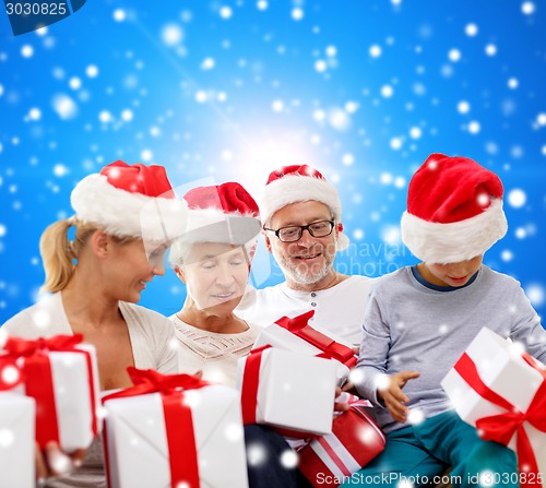 Image of happy family in santa helper hats with gift boxes