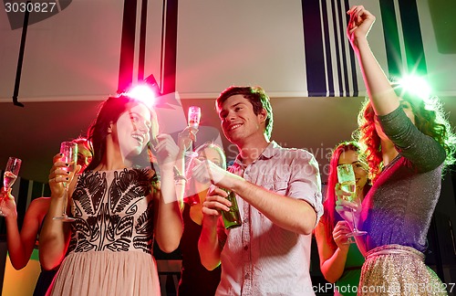 Image of smiling friends with wine glasses and beer in club