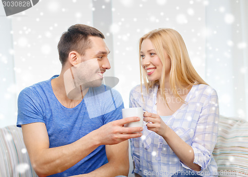 Image of smiling couple with cup of tea or coffee at home