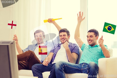 Image of happy male friends with flags and vuvuzela