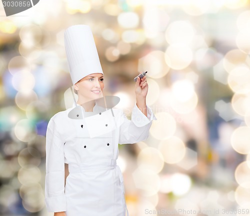Image of smiling female chef writing something on air