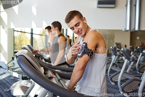 Image of man with smartphone exercising on treadmill in gym