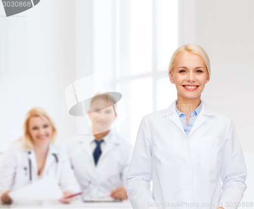 Image of smiling female doctor with group of medics