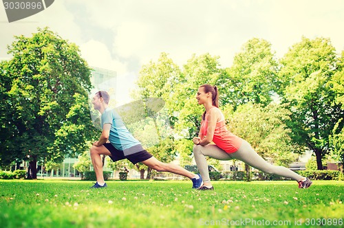 Image of smiling couple stretching outdoors