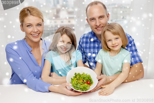Image of happy family with two kids showing salad in bowl