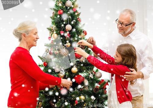 Image of smiling family decorating christmas tree at home
