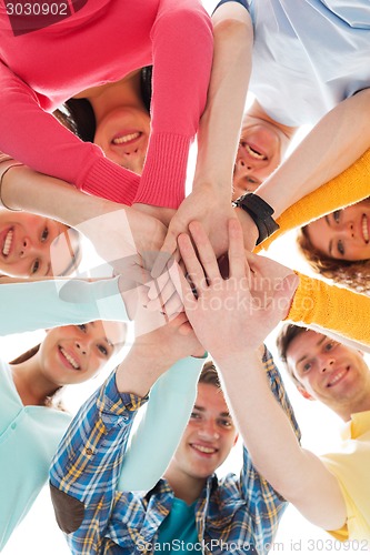 Image of smiling teenagers with hands on top of each other