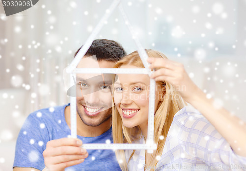 Image of smiling couple holding house model at home