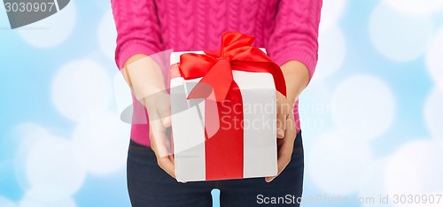 Image of close up of woman in pink sweater holding gift box