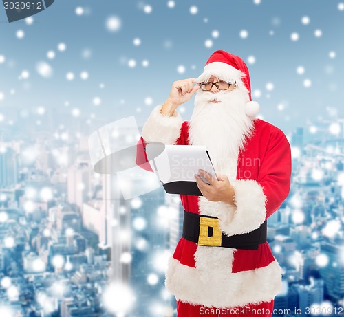 Image of man in costume of santa claus with notepad