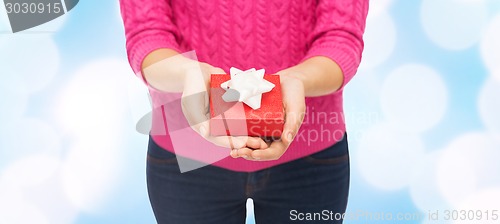 Image of close up of woman in pink sweater holding gift box