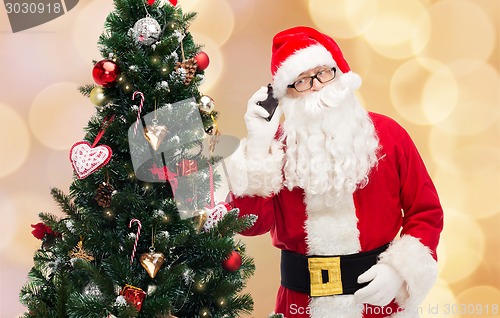 Image of santa claus with smartphone and christmas tree