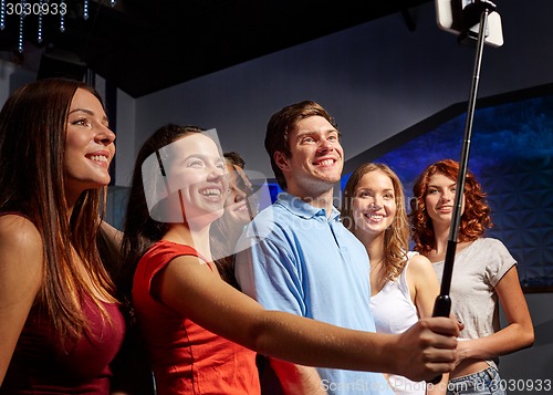 Image of friends with smartphone taking selfie in club