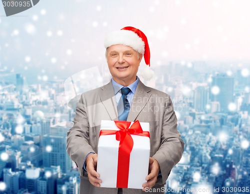 Image of smiling man in suit and santa helper hat with gift