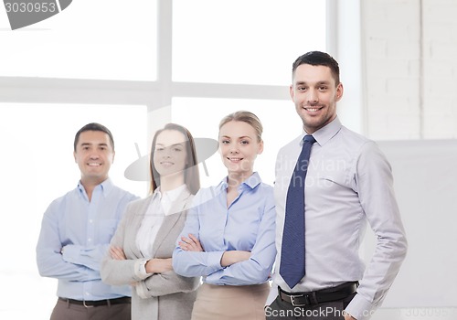 Image of smiling businessman in office with team on back