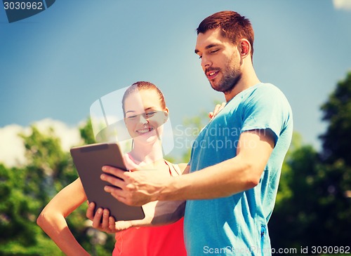 Image of smiling couple with tablet pc outdoors