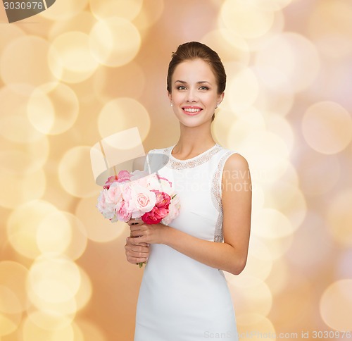 Image of smiling woman in white dress with bouquet of roses