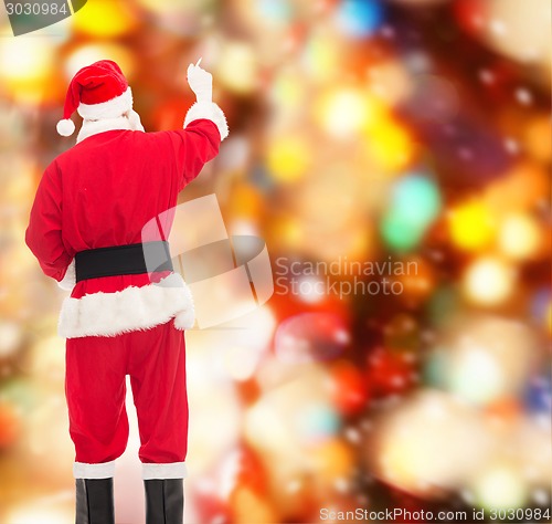 Image of man in costume of santa claus writing something