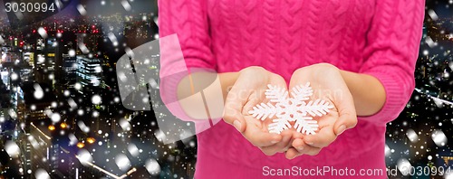 Image of close up of woman in sweater holding snowflake