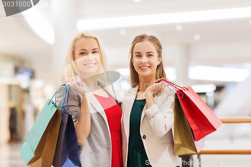 Image of happy young women with shopping bags in mall