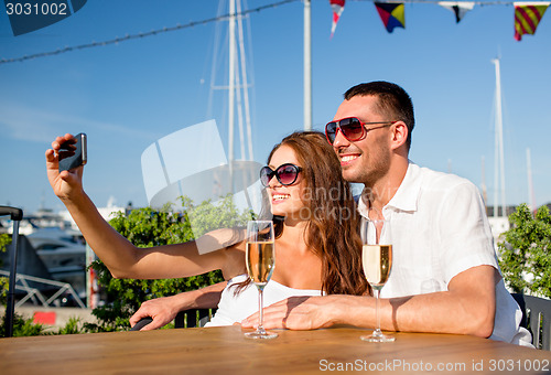 Image of smiling couple drinking champagne at cafe
