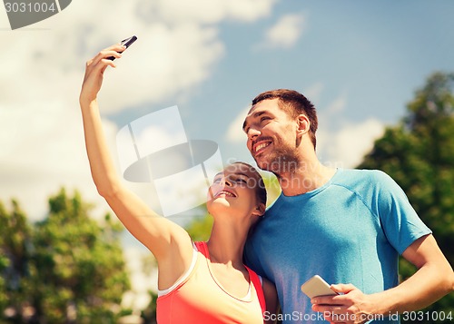 Image of two smiling people with smartphones outdoors