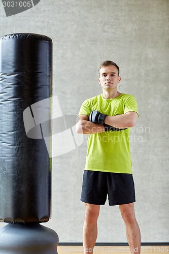 Image of man with boxing gloves and punching bag in gym