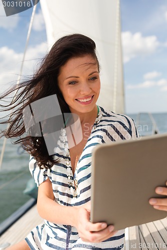 Image of smiling woman sitting on yacht with tablet pc