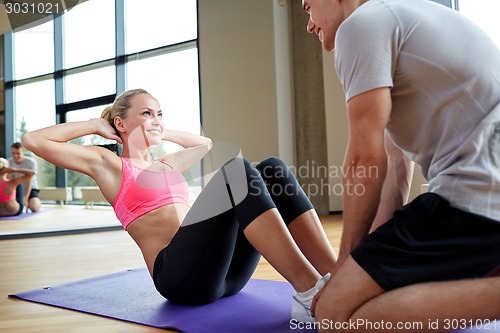 Image of woman with personal trainer doing sit ups in gym