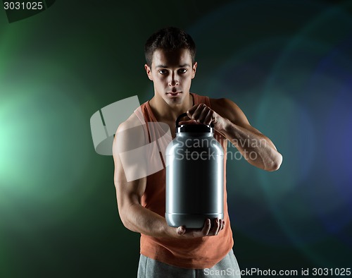 Image of young male bodybuilder holding jar with protein
