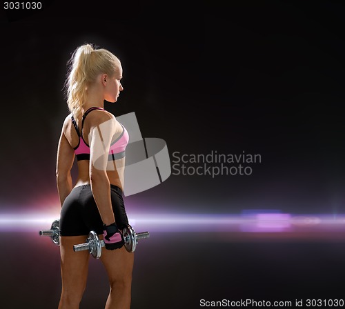 Image of sporty woman with heavy steel dumbbells