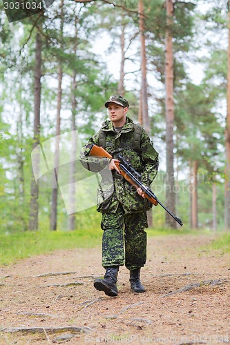 Image of young soldier or hunter with gun in forest