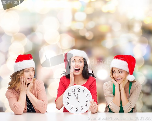 Image of smiling women in santa helper hat with clock