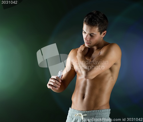 Image of young male bodybuilder applying pain relief gel