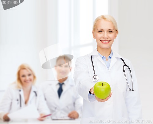 Image of smiling female doctor with green apple