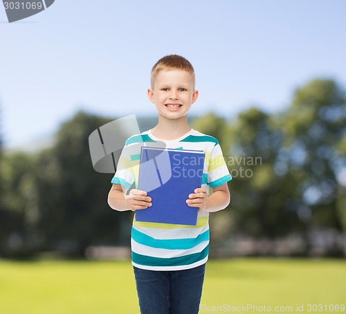 Image of smiling little student boy with blue book