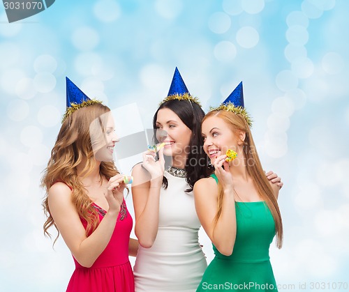 Image of smiling women in party caps blowing to whistles