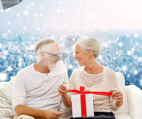 Image of happy senior couple with gift box at home