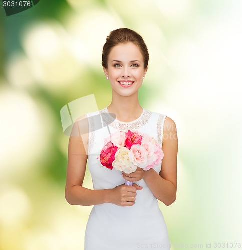 Image of smiling woman in white dress with bouquet of roses